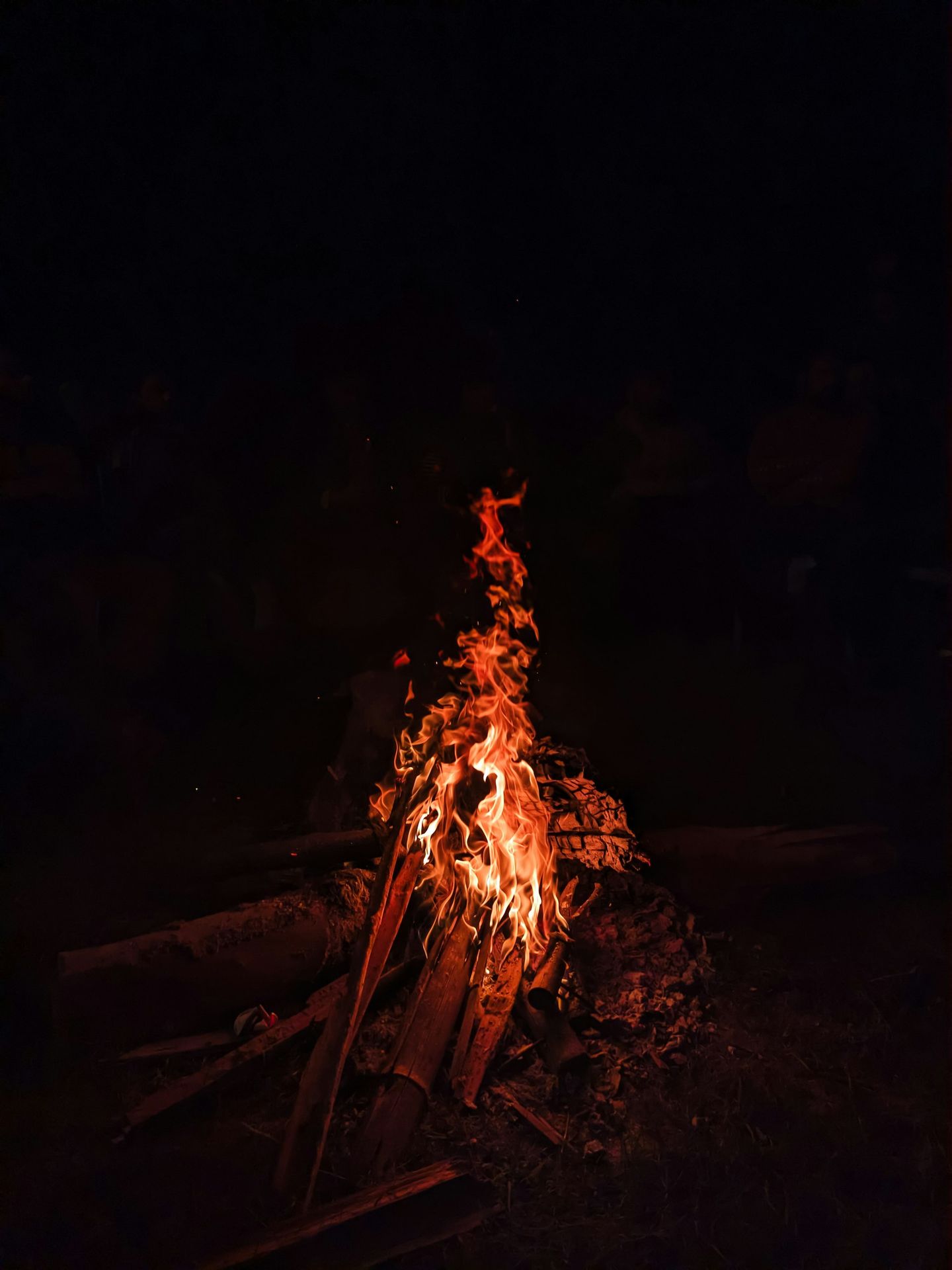 A campfire in the dark with a person standing next to it